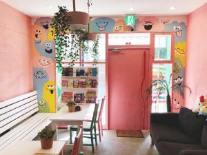 Guest House Yadomaru في أوساكا: غرفة طعام مع طاولة وجدار وردي
