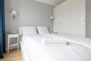 a white bedroom with a large white bed with towels on it at Baltic Apartments Seaside Residence in Gdańsk