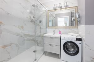 a bathroom with a washing machine and a shower at Baltic Apartments Seaside Residence in Gdańsk