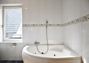 eine weiße Badewanne in einem Badezimmer mit Fenster in der Unterkunft Žalias namas in Palanga + 87 Fotos