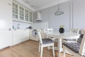 a white kitchen with a white table and chairs at Baltic Apartments Seaside Residence in Gdańsk +24 photos
