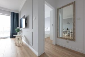 a white hallway with a mirror and a table at Baltic Apartments Seaside Residence in Gdańsk