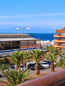 a parking lot with palm trees in front of a building at Ocean View Apartment in Palm-mar
