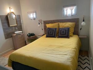 um quarto com uma grande cama amarela e um lavatório em Le Moulin de Saint-Julien em Saint-Didier-sur-Chalaronne