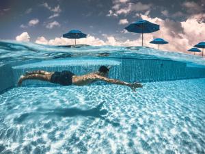 a man laying in a swimming pool in the water at Sunset Caribe Belize in San Pedro