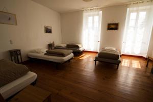 3 camas num quarto com pisos e janelas em madeira em Gite d'étape Les Diligences em Roquefixade