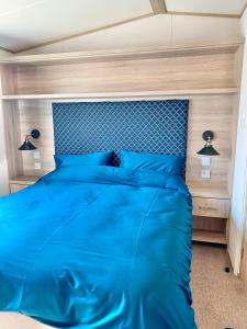 a bed with a blue comforter in a bedroom at Beachfront Lodge, Lossiemouth Bay in Lossiemouth