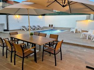 AiosにあるVivienda adosada con piscina cerca de la playaの木製テーブルと椅子、パラソル、プール付)