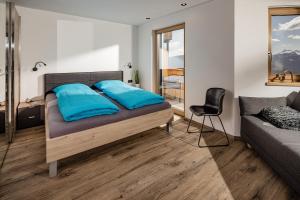 a bedroom with a bed with blue pillows and a chair at Sweet Dolomiti Sonneck in Maranza