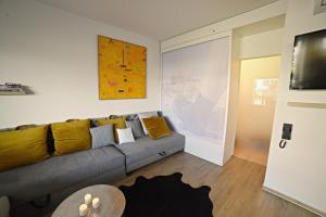 - un salon avec un canapé gris et des oreillers jaunes dans l'établissement Apartmán PERGOLA, à Mikulov