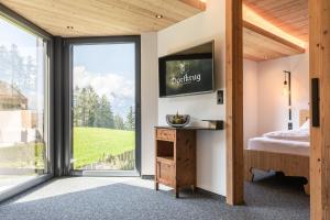 een slaapkamer met een grote glazen schuifdeur en een televisie bij s'Hoamatl Dorfkrug Appartements in Seefeld in Tirol