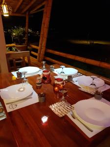 a wooden table with white plates and glasses on it at Hotel Sotavento in Montañita
