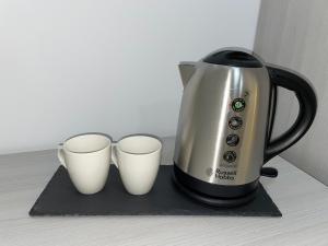 a coffee pot and two cups on a counter at La Veranda Hotel in Larnaca