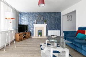 een woonkamer met een blauwe bank en een open haard bij Stylish House & Work and Leisure inc FREE Parking & BHX Airport in Coventry