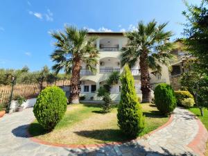 a house with palm trees in front of it at Hotel Pefko in Neos Marmaras