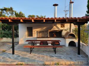 a picnic table under a pavilion with a pizza oven at Hotel Pefko in Neos Marmaras