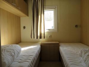 two beds in a small room with a window at Chalet 3 in Meliskerke +4 photos