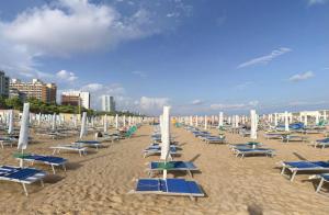 リニャーノ・サッビアドーロにあるOlaszelmeny Beach Caravans Lignano Sabbiadoroのビーチの椅子とパラソルの束