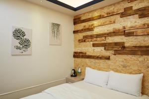 a bedroom with a wooden accent wall and a bed at At Tainan Inn in Tainan