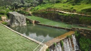 une rivière avec une cascade et un pont sur celle-ci dans l'établissement Casas do Almourão, à Foz do Cobrão