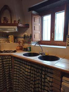 LA HUETA Bajo في Orcera: طاولة مطبخ مع حوض ونوافذ