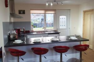 a kitchen with red stools at a kitchen counter at Uig Chalets Idrigill Hill Chalet in Uig