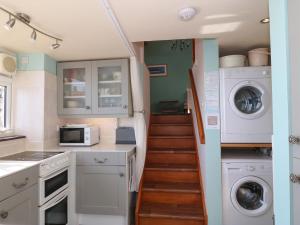a kitchen with a staircase with a washer and dryer at The Grain Store in Abersoch