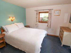 a bedroom with a white bed and a window at The Grain Store in Abersoch