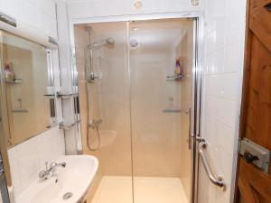 a bathroom with a glass shower and a sink at The Grain Store in Abersoch