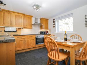a kitchen with wooden cabinets and a wooden table with chairs at Kiln How in Keswick