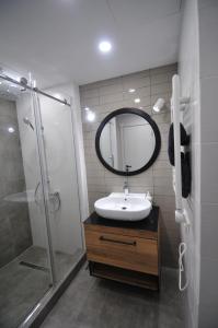 uma casa de banho com um lavatório, um chuveiro e um espelho. em Sea view Apartment near to the Dancing and Music Fountains em Batumi