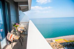 uma varanda com uma mesa e cadeiras com vista para o oceano em Sea view Apartment near to the Dancing and Music Fountains em Batumi