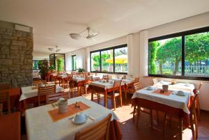 un restaurante con mesas, sillas y ventanas grandes en Hotel Versilia, en Lido di Camaiore