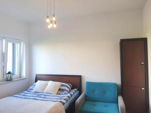 a bedroom with a bed and a blue chair at Passo Rowy in Rowy