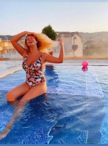 una mujer en traje de baño sentada en una piscina en Queen Kodre Apartments, en Ulcinj