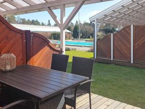 a wooden table and chairs in a backyard with a pool at 4 person holiday home in Nex in Strandby Gårde