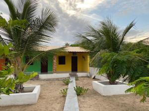 a small yellow and green house with two palm trees at Chalés Porto do Céu in Aracati
