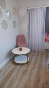 a room with a table and a pink chair at Apartament Wilkońskiego in Inowrocław