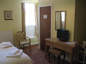 Habitación de hotel con cama y escritorio con TV. en The Red Lion Hotel en Bredwardine