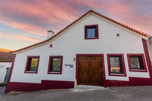 a white and red house with a wooden door at Gamboas Place in Olhalvo