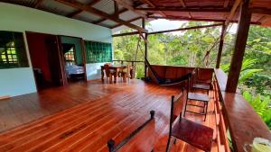 a wooden deck with chairs and a hammock on a house at GreenPoint Drake Bay in Drake