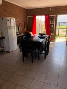 a kitchen with a table and chairs and a refrigerator at Cabaña Bello Horizonte, 3 5 3 5 0 8 5 9 0 6 ,dos dormitorios con cochera privada doble, asador y parque in Villa María