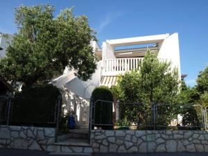 a fence in front of a white building with trees at Apartment Željka-25m from beach in Zaglavice