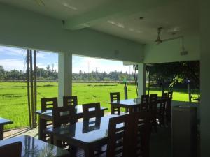 een restaurant met tafels en stoelen en uitzicht op een veld bij Thisara Guest House in Polonnaruwa