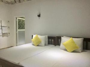 een slaapkamer met een bed met 2 gele kussens bij Thisara Guest House in Polonnaruwa