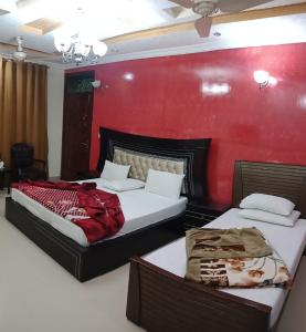 two beds in a room with a red wall at Butt Lodges 2 in Islamabad