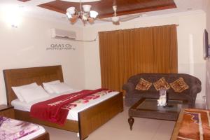 a bedroom with a bed and a couch and a table at Butt Lodges 2 in Islamabad