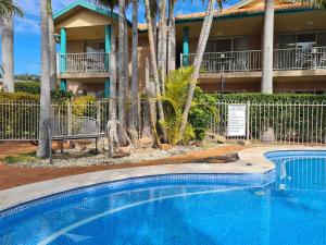 a swimming pool in front of a resort with palm trees at Beaches Serviced Apartments in Nelson Bay