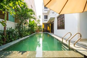 a swimming pool in a building with an umbrella at Spring Garden Villa Hoi An in Hoi An
