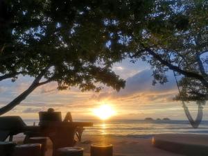 a person sitting at a table on the beach watching the sunset at Koh Chang Bailan Beach Resort in Ko Chang